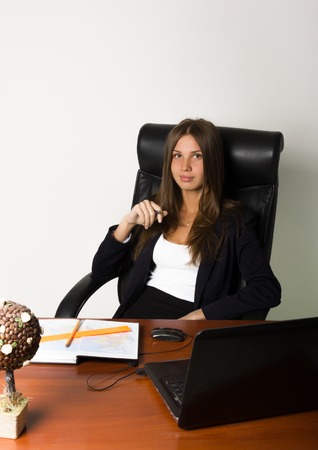business woman in a suit sitting at a desk. on the table laptop and notebook.の写真素材
