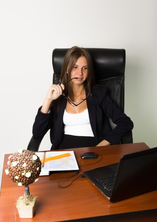 business woman in a suit sitting at a desk. on the table laptop and notebook.の写真素材