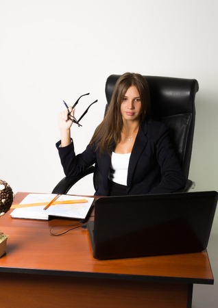 business woman in a suit sitting at a desk. on the table laptop and notebook.の写真素材