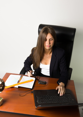 business woman in a suit sitting at a desk. on the table laptop and notebook.の写真素材