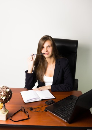 business woman in a suit sitting at a desk. on the table laptop and notebook.の写真素材