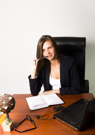 business woman in a suit sitting at a desk. on the table laptop and notebook.の写真素材