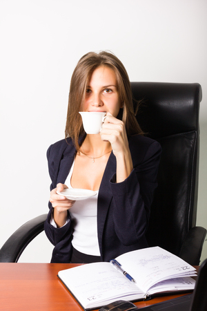 Pretty woman in a business suit sitting at a desk with computer. Studio shot.の写真素材