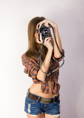 beautiful smiling brunette girl with a camera is dressed in shorts and a shirtの写真素材