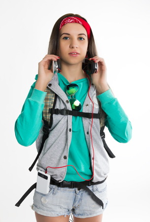 Young brunette female student standing and listening to music from your device. Beautiful young backpackerの写真素材