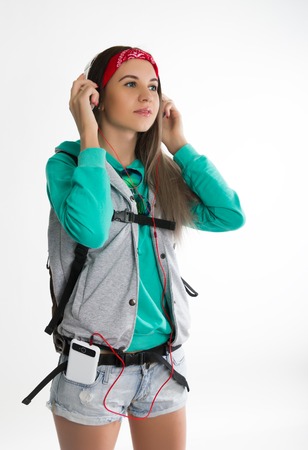 Young brunette female student standing and listening to music from your device. Beautiful young backpackerの写真素材