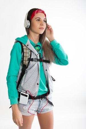 Young brunette female student standing and listening to music from your device. Beautiful young backpackerの写真素材