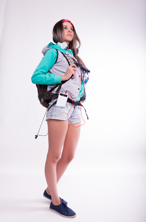 Young brunette female student standing and listening to music from your device. Beautiful young backpackerの写真素材