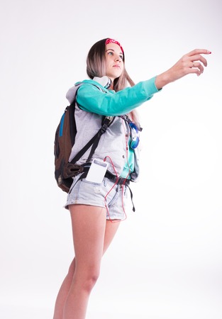 Young brunette female student standing and listening to music from your device. Beautiful young backpackerの写真素材