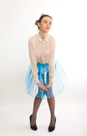 Full length portrait of a beautiful sexy slim model in a blue skirt and white blouse transparent, in stockings and gartersの写真素材