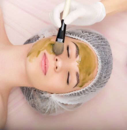 beautician does cosmetic mask on the patient's face. Professional consultation.の写真素材