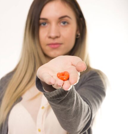 young woman holding the drugs at arm's length. she offers taste of the tabletsの写真素材