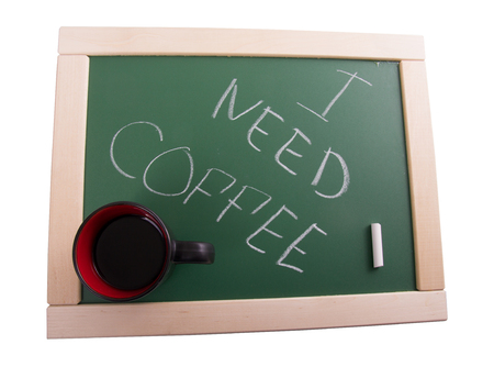 A chalkboard sign and black cup on a white background - I need coffee.の写真素材