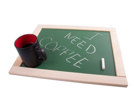 A chalkboard sign and black cup on a white background - I need coffee.の写真素材