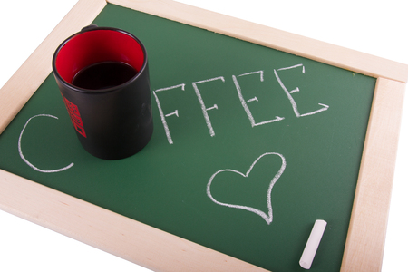 inscription on the chalkboard and black cup on a white background - coffee.の写真素材