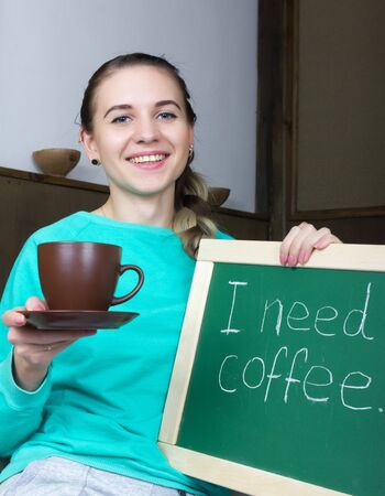 beautiful slim woman in a tracksuit with chalkboard, i need coffeeの写真素材
