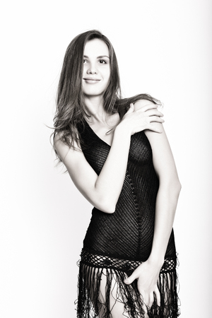 Black and white. Beautiful sexy brunette girl in studio on a white background in a transparent black dressの写真素材