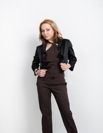 Beautiful young leggy blonde in a  brown top, black jacket and pants posing.の写真素材