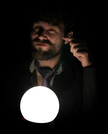 bearded man in the dark, holding in front of a lamp, expresses different emotions. shows the index finger.の写真素材