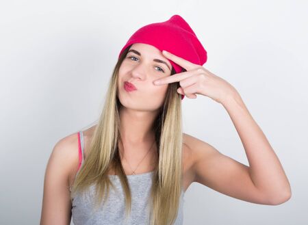 teenager girl in denim shorts and a gray T-shirt and a pink knit hat, tied at the hips plaid shirt. showing sign victory.の写真素材