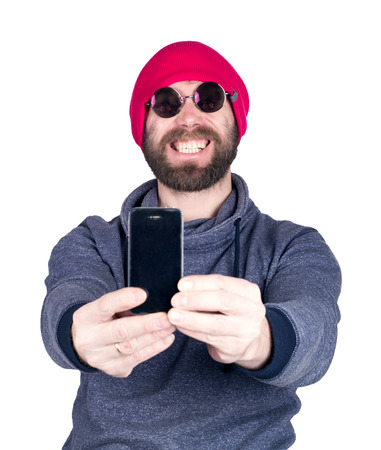 Fashion hipster cool man in sunglasses and colorful clothes holding a phone in front of him and pictures of themselves, selfie.の写真素材