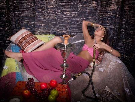 beautiful girl in eastern dress smokes a hookah.の写真素材