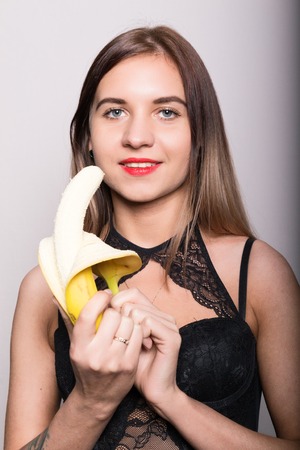 Young amazed woman in lacy lingerie holding a banana, she is going to eat a banana.の写真素材