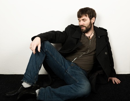 Handsome bearded elegant business man in a jacket, jeans and a woolen coat posing. feshion concept.