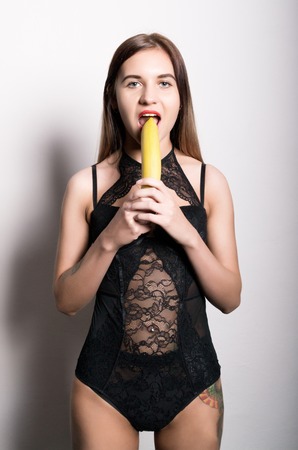 Young amazed woman in lacy lingerie holding a banana, she is going to eat a banana.の写真素材