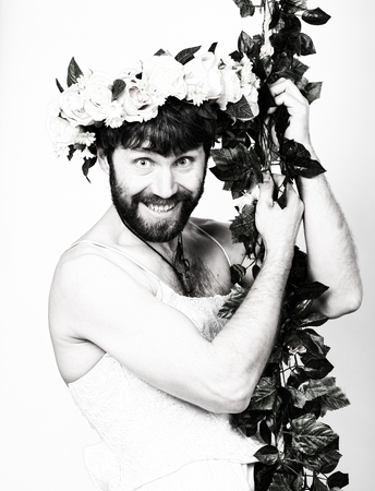 bearded man in a woman's wedding dress on her naked body, clinging to the vine. on his head a wreath of flowers. funny bearded bride, black and white.の写真素材