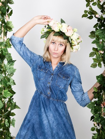 beautiful blonde girl dressed in denim sundress, her head a wreath of flowers.の写真素材