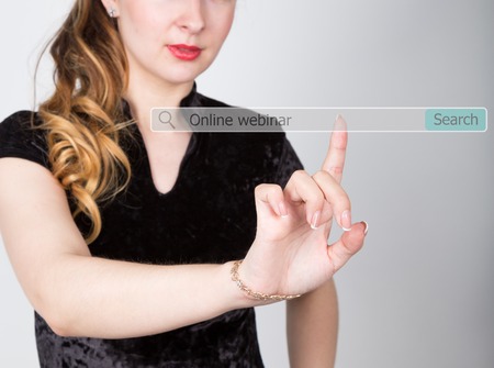 Online webinar written in search bar on virtual screen. technology, internet and networking concept. woman in a black business shirt presses button on virtual screens.の写真素材
