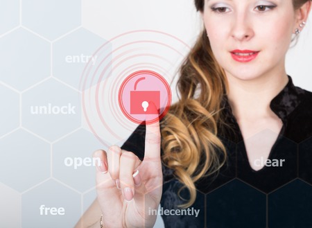 technology, internet and networking concept. beautiful woman in a black business shirt. woman presses unlock button on virtual screens.の写真素材