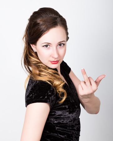 young woman's portrait with different happy emotions. she showing middle finger, provocative gesture.の写真素材