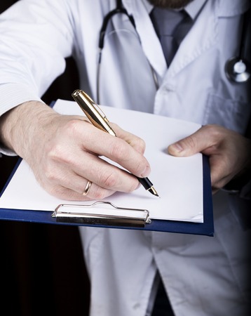 close-up hands of a medical doctor, the doctor signs a handle documents. Doctor writes medical history. write a prescription patient data history.の写真素材