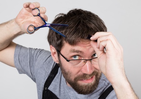 male barber cuts himself, looking at the camera like the mirror. stylish professional hairdresser expresses different emotions.の写真素材
