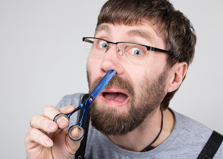 male barber cuts his own hair in the nose, looking at the camera like the mirror. stylish professional hairdresser expresses different emotions.の写真素材