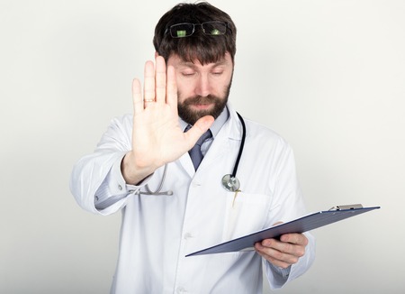close-up portret of a Doctor holding a map-case for note, stethoscope around his neck. He held up his hand, palm forward. different emotions.の写真素材