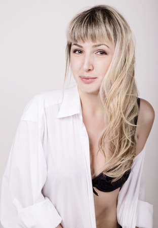 close-up portrait of a beautiful sexy woman in a white shirt over his naked body, in black lace lingerie and stockings.の写真素材