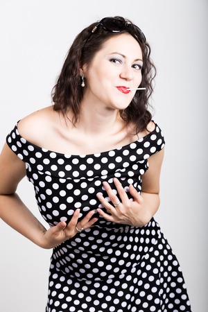 Portrait of happy beautiful young woman licking chupa chups. pretty woman with heart shaped lollipop.の写真素材