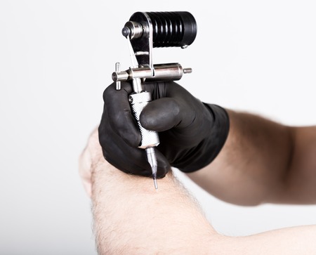 close-up of Tattooist hands in black gloves with tattoo machine.の写真素材