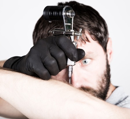 close-up of Tattooist hands in black gloves with tattoo machine.の写真素材