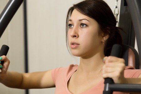 young woman is engaged in sports and gymnastics in the gym.