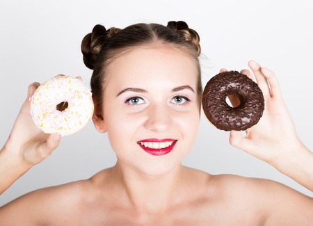 girl in bright makeup eating a tasty donut with icing. Funny joyful woman with sweets, dessert. dieting concept. junk food.の写真素材