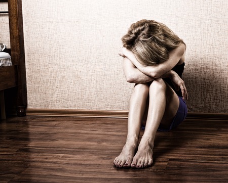 Sad woman sitting alone in a empty room next to the bed. domestic violence.の写真素材