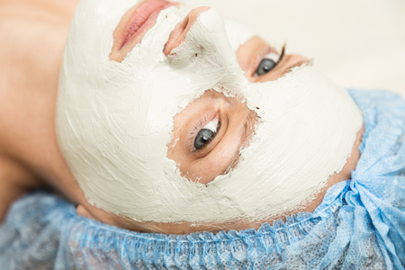 Young woman lying down in a spa salon and having a facial beauty treatment. The cosmetic procedures for the face. Beauty treatments in the spa salon. Facial Skin Care.の写真素材