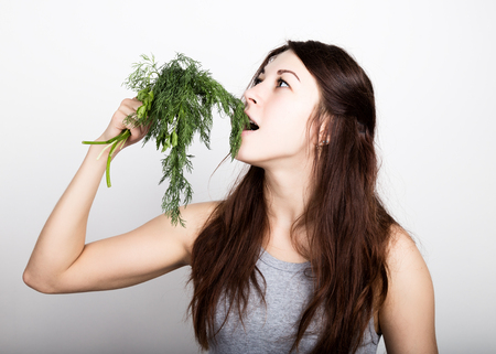 beautiful young woman eating an dill. healthy food - strong teeth concept.の写真素材