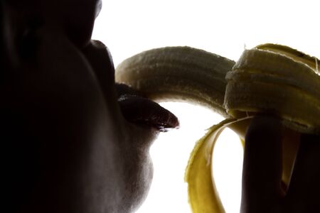 Young amazed woman in lacy lingerie holding a banana, she is going to eat a banana. she sucks a banana.の写真素材