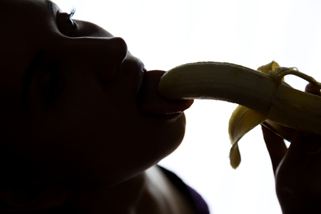 Young amazed woman in lacy lingerie holding a banana, she is going to eat a banana. she sucks a banana.の写真素材