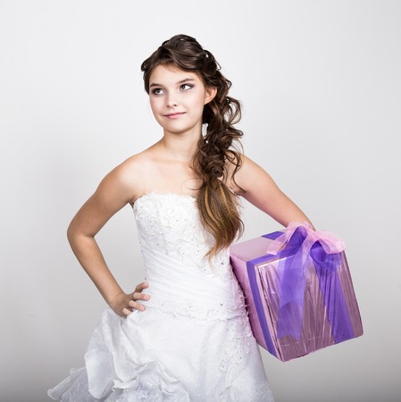 little girl in a white dress holding a box with a gift.